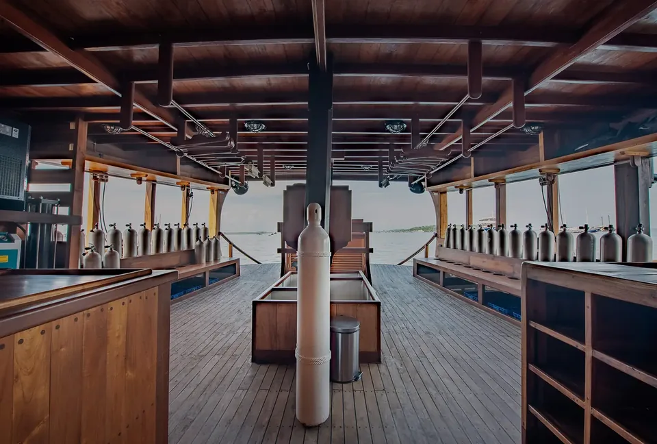 Dive deck of a liveaboard with rows of scuba cylinders and wooden benches